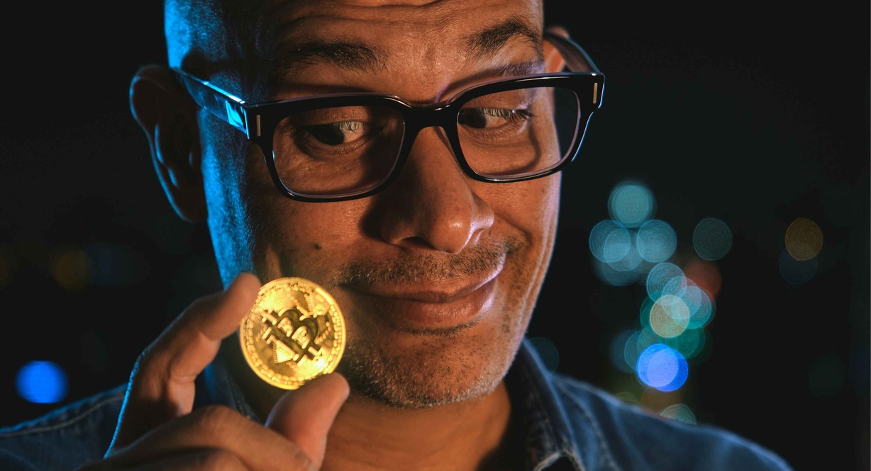 Homme tenant une pièce de bitcoin pour investir en crypto