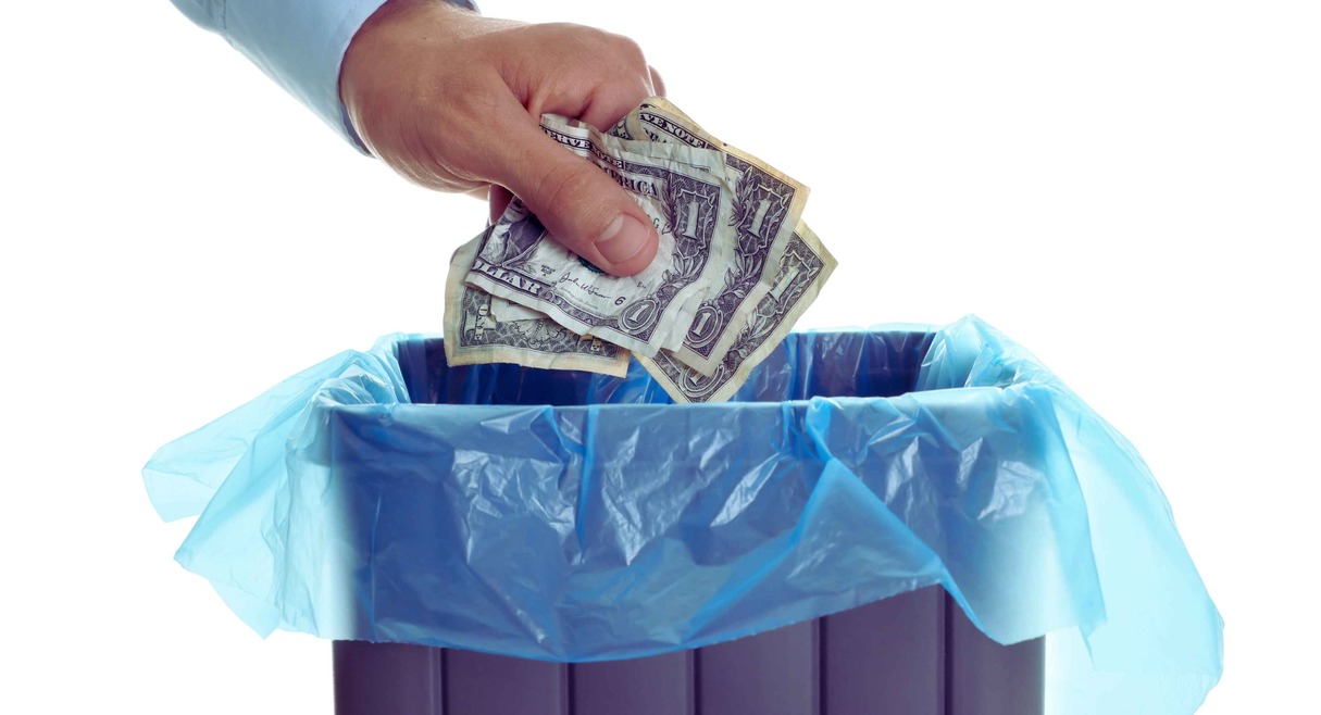 Homme jetant des billets de banque dans une poubelle illustrant le concept de fortune improductive