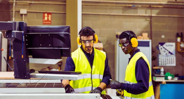 Ouvriers travaillant sur une machine CNC dans une usine industrielle illustrant le Groupe Strauss à Saint-Doulchard