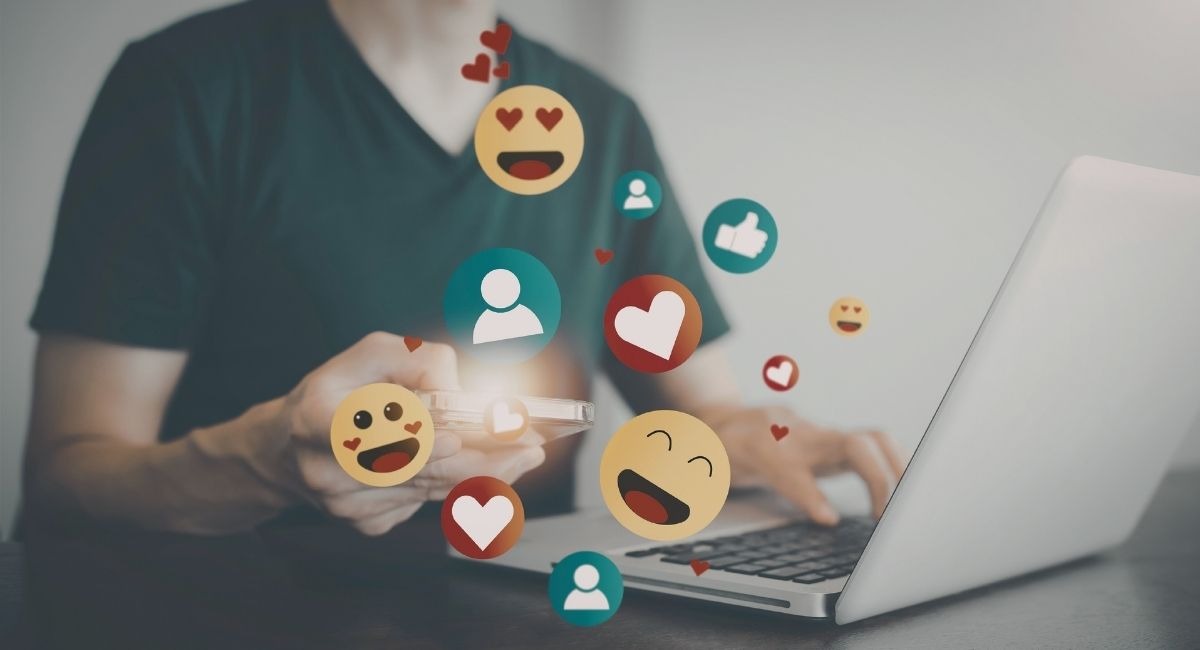 Homme utilisant un laptop et smartphone avec icônes de réseaux sociaux