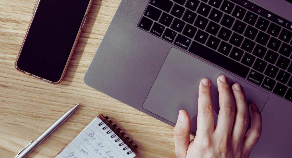 Vue aérienne d'un bureau avec MacBook, smartphone et carnet de notes manuscrites