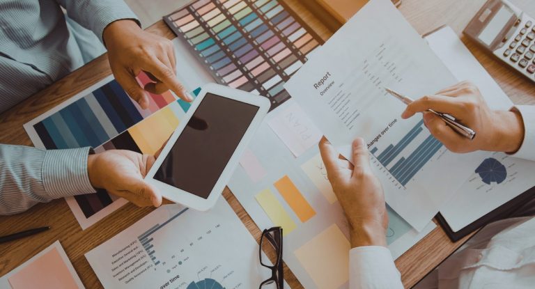 Vue aérienne d'une équipe marketing discutant de stratégie autour de graphiques et d'une tablette