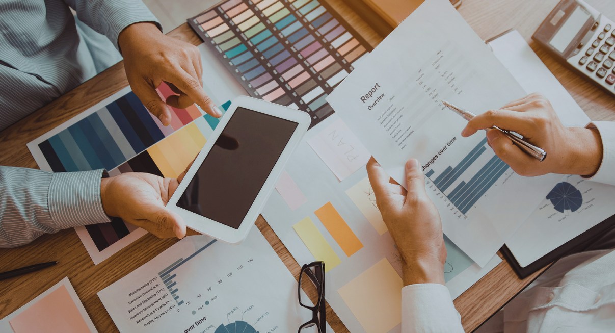 Vue aérienne d'une équipe marketing discutant de stratégie autour de graphiques et d'une tablette