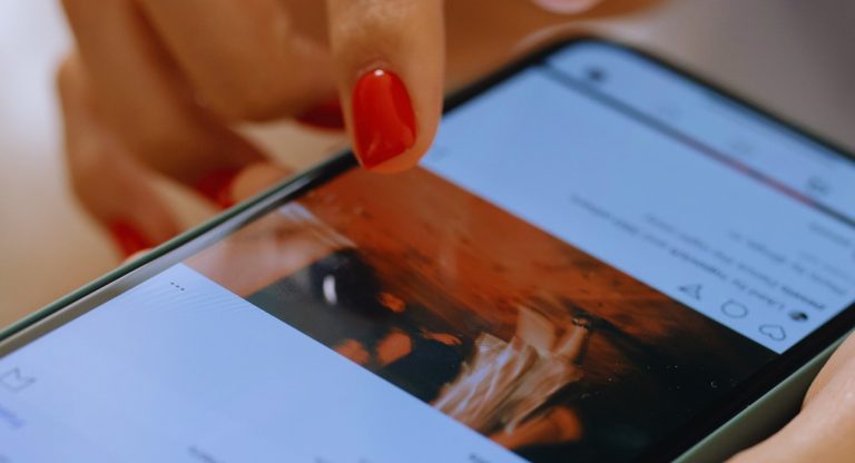 Main de femme faisant défiler le fil d'actualité Instagram sur un téléphone