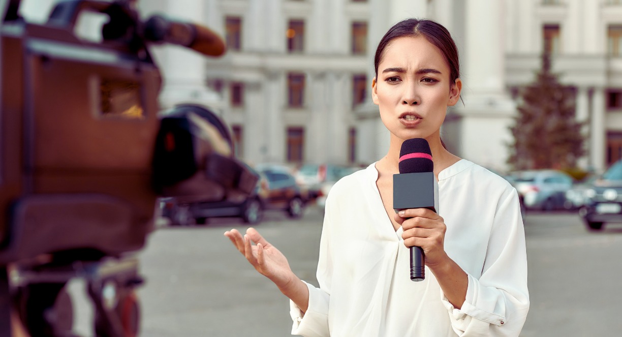 Journaliste femme présentant un reportage en direct devant une caméra de télévision