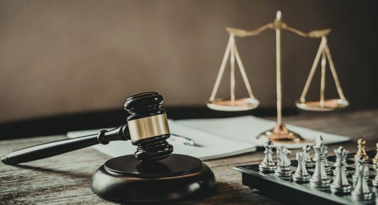 Marteau de juge en bois et balance de la justice dorée sur un bureau de tribunal