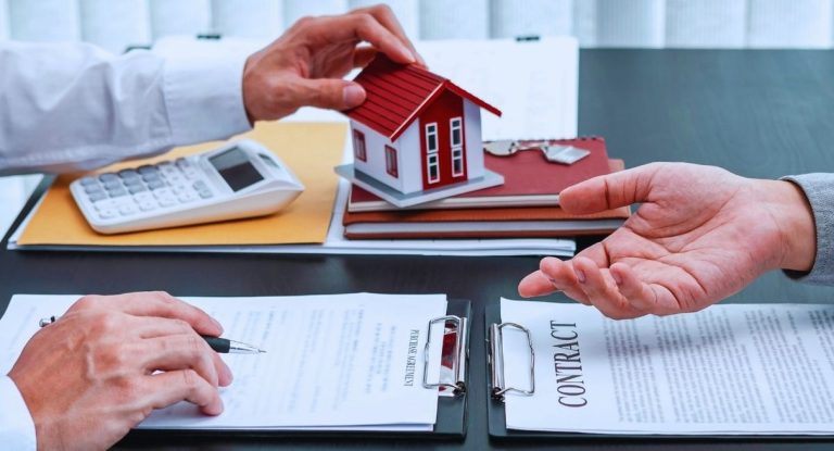 Contrat de pret immobilier, calculatrice, cles et maquette de maison poses sur un bureau lors d'une signature