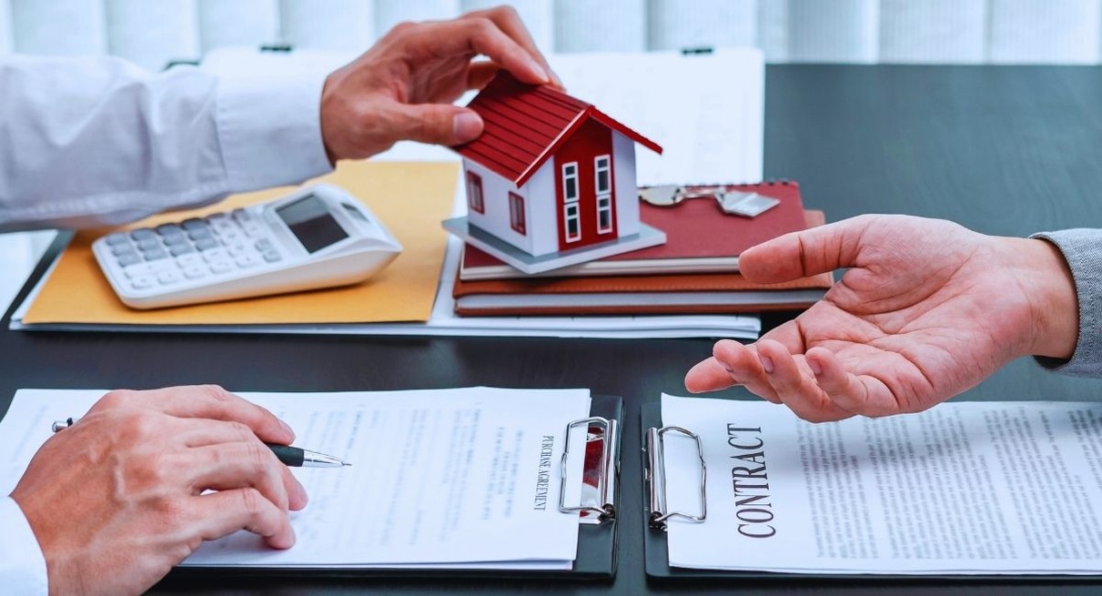 Contrat de pret immobilier, calculatrice, cles et maquette de maison poses sur un bureau lors d'une signature