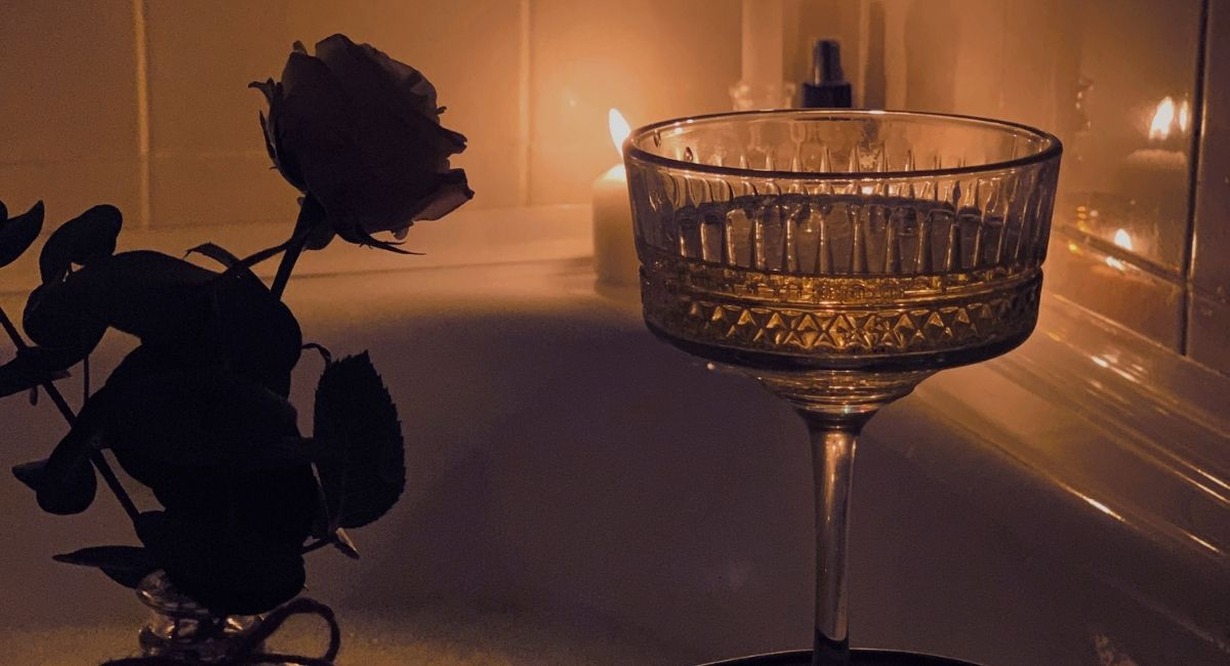 Coupe de champagne et rose près d'un bain aux chandelles pour une ambiance romantique