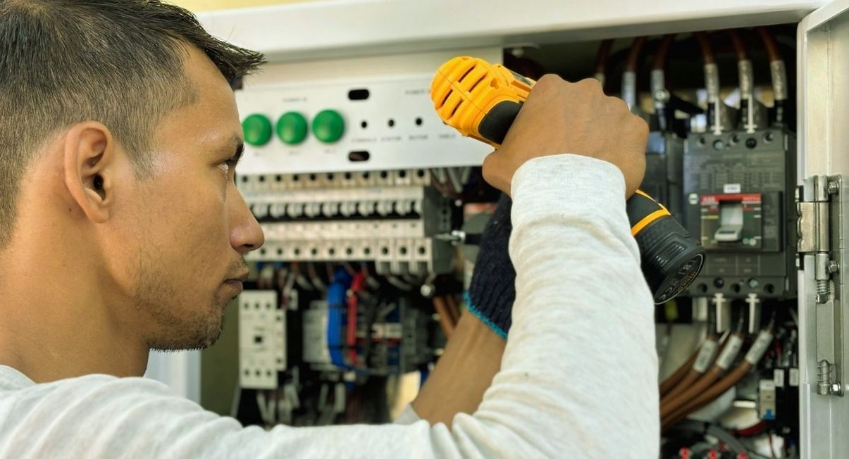 Electricien travaillant sur un tableau electrique avec une visseuse