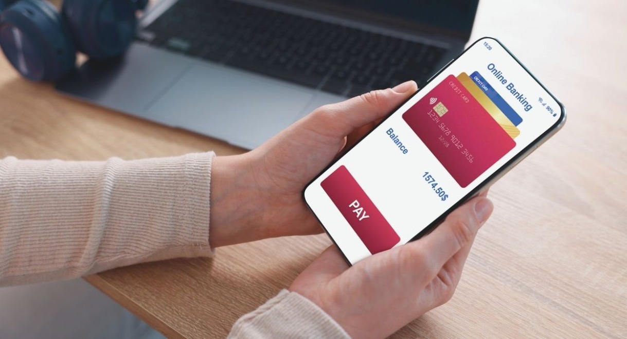 Mains tenant un smartphone avec une application de paiement bancaire ouverte