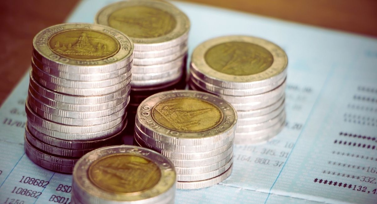 Piles de pièces de monnaie posées sur un livret de compte d'épargne