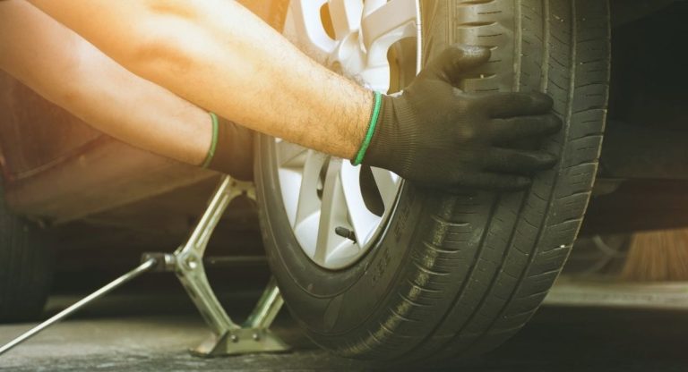 Mains gantees dun mecanicien changeant un pneu de voiture