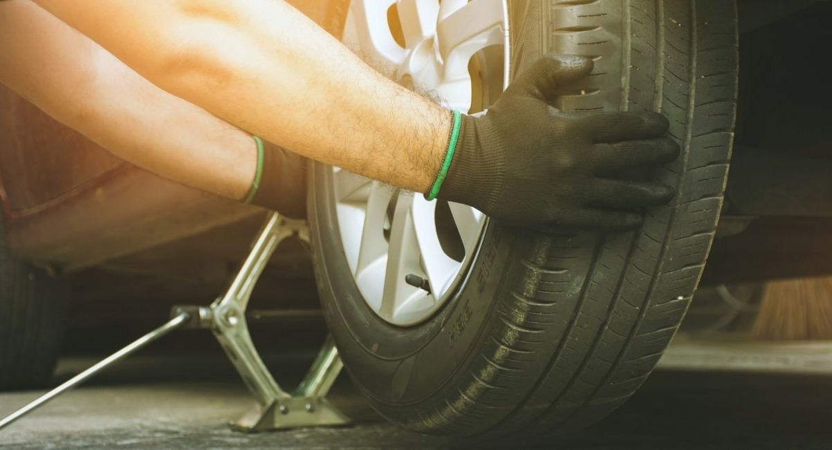 Mains gantees dun mecanicien changeant un pneu de voiture