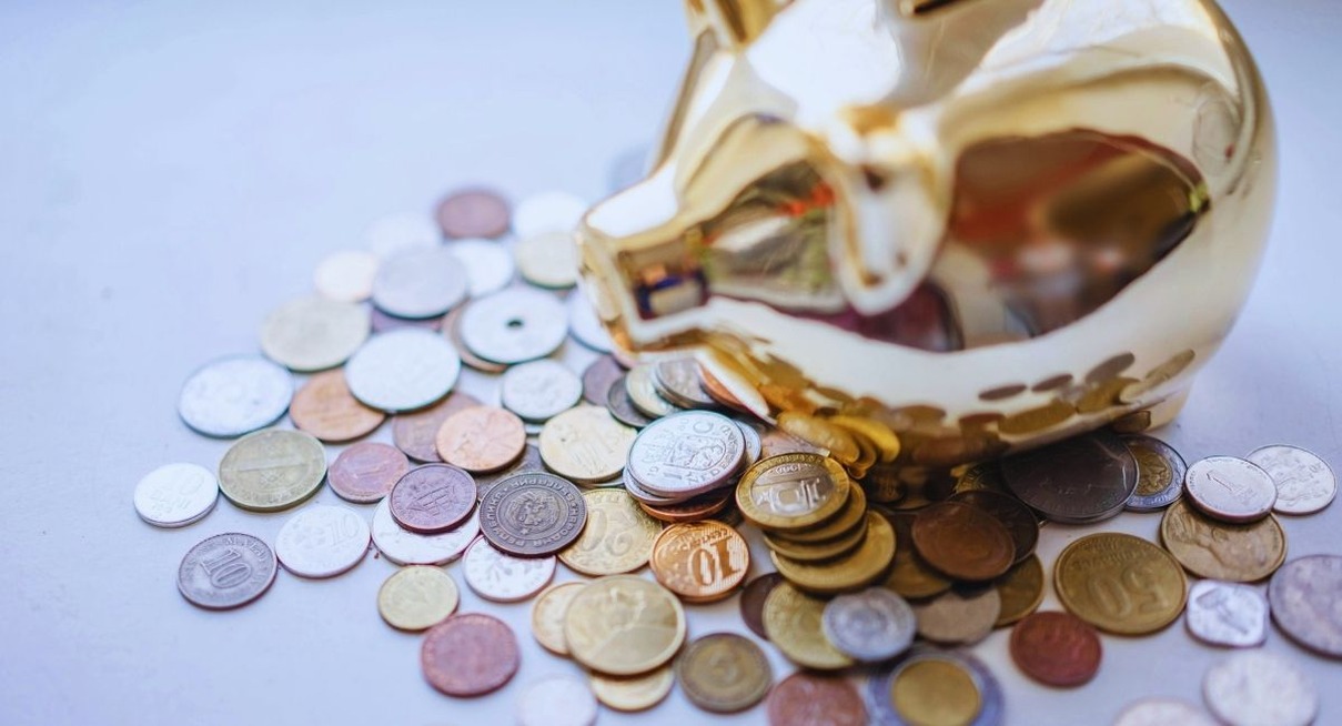 Tirelire dorée renversée avec des pièces de monnaie éparpillées