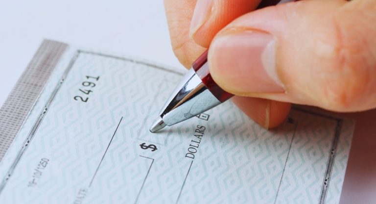 Main tenant un stylo pour remplir le montant sur un cheque